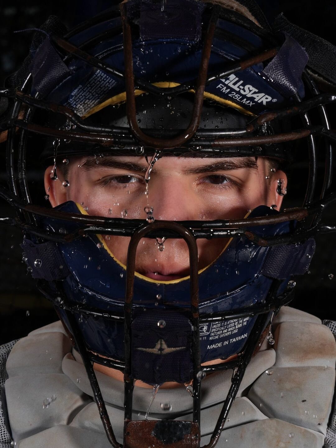 Close-up of a baseball catcher in his mask with water drops on his face