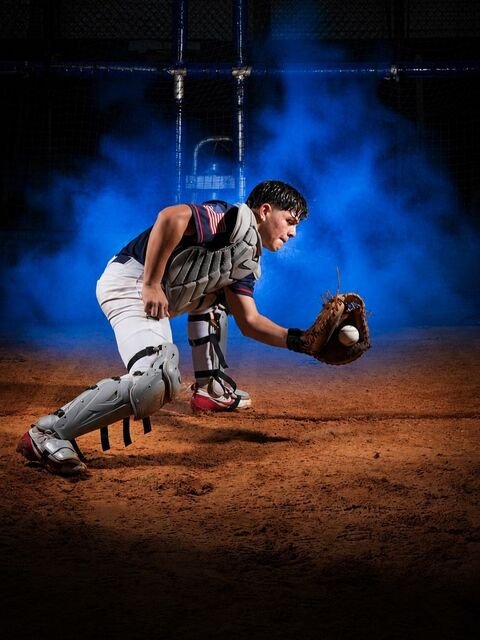 Catcher in blocking position over home plate with blue smoke behind