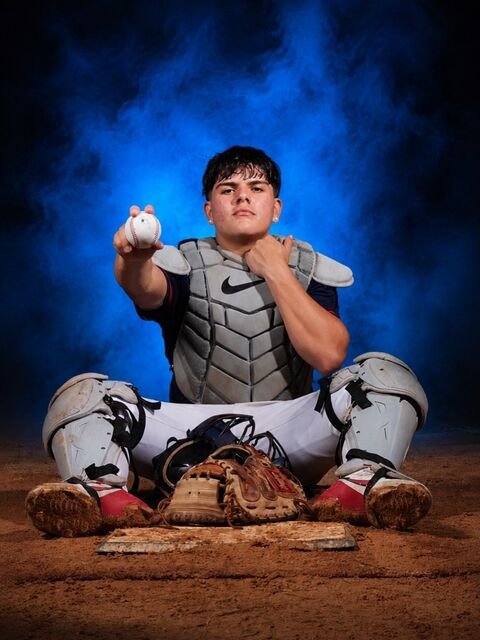 Catcher sitting behind home plate showing the ball to the camera