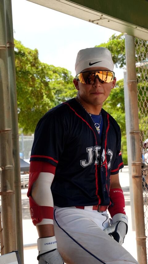 Baseball player in a navy uniform next to the dugout