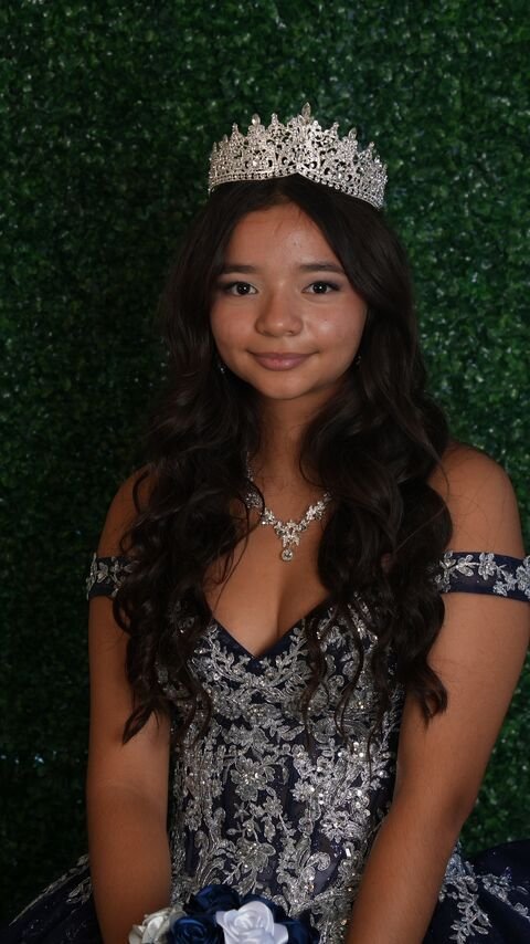 Portrait of the quinceañera wearing a tiara and a navy gown with silver embroidery
