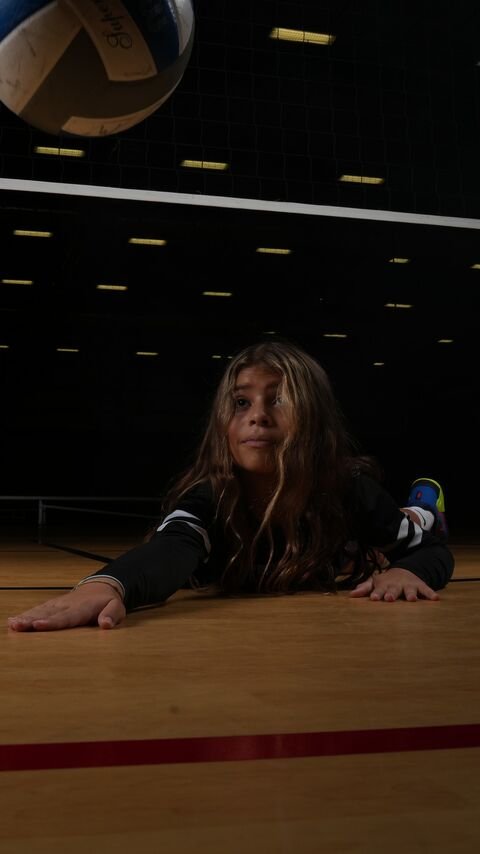 Player lying on the court with the ball suspended in the air