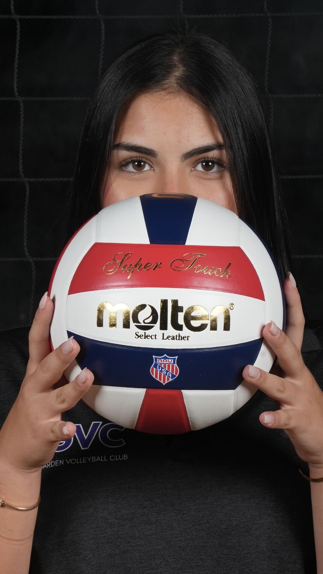 Player holding a volleyball in front of her face