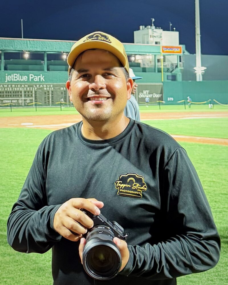 Richard Tappin holding his Sony camera on a baseball field at night